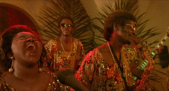 Movie still from “Mississippi Masala” (1991), directed by Mira Nair – A group of people in colorful clothing and sunglasses; Medium shot, Over the shoulder angle
