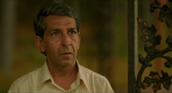 Movie still from “Mississippi Masala” (1991), directed by Mira Nair – An older man is looking into the distance; Close Up shot, Over the shoulder angle