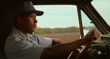 Movie still from “Mississippi Masala” (1991), directed by Mira Nair – A man sitting in the driver's seat of a car driving down a road; Close Up shot, Low angle