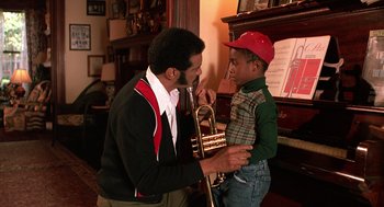 Movie still from “Mo' Better Blues” (1990), directed by Spike Lee – A man and a young boy are playing a trumpet together; Medium shot, High angle