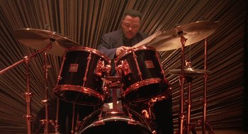 Movie still from “Mo' Better Blues” (1990), directed by Spike Lee – A man is playing drums in a room; Medium shot, Low angle