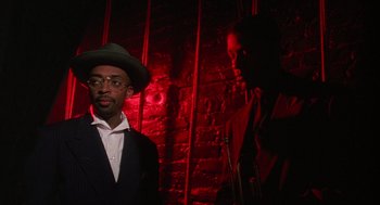 Movie still from “Mo' Better Blues” (1990), directed by Spike Lee – A man wearing a suit and hat standing in front of a brick wall; Close Up shot, Low angle