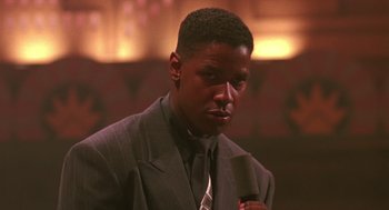 Movie still from “Mo' Better Blues” (1990), directed by Spike Lee – A man in a suit and tie holding a microphone; Close Up shot, Low angle