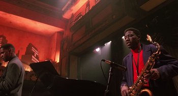 Movie still from “Mo' Better Blues” (1990), directed by Spike Lee – A man standing in front of a microphone and a piano; Medium shot, Low angle