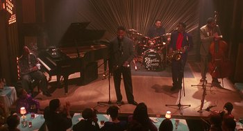 Movie still from “Mo' Better Blues” (1990), directed by Spike Lee – A group of people on a stage with microphones; Extreme Wide shot, High angle