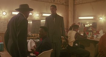 Movie still from “Mo' Better Blues” (1990), directed by Spike Lee – A man in a suit standing next to another man in a suit; Medium shot, Over the shoulder angle
