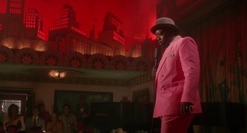 Movie still from “Mo' Better Blues” (1990), directed by Spike Lee – A man in a pink suit and hat holding a microphone; Medium shot, Over the shoulder angle