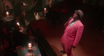 Movie still from “Mo' Better Blues” (1990), directed by Spike Lee – A man in a pink suit and hat singing into a microphone; Medium shot, High angle