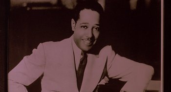 Movie still from “Mo' Better Blues” (1990), directed by Spike Lee – A man in a suit and tie smiling for the camera; Close Up shot, Low angle