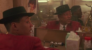 Movie still from “Mo' Better Blues” (1990), directed by Spike Lee – A man in a red jacket and a black hat looking in a mirror; Close Up shot, Over the shoulder angle