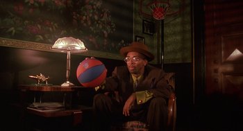 Movie still from “Mo' Better Blues” (1990), directed by Spike Lee – A man sitting in a chair holding a basketball; Medium shot, Low angle