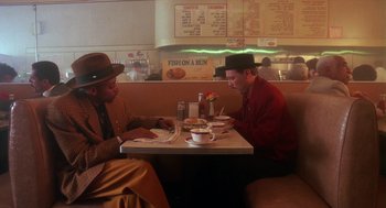 Movie still from “Mo' Better Blues” (1990), directed by Spike Lee – Two men sitting at a table in front of a menu; Medium shot, High angle