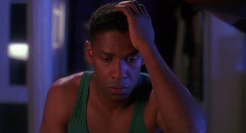 Movie still from “Mo' Better Blues” (1990), directed by Spike Lee – A man with a green tank top holding his hand to his head; Close Up shot, Over the shoulder angle