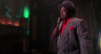 Movie still from “Mo' Better Blues” (1990), directed by Spike Lee – A man wearing a suit and hat holding a microphone; Medium shot, Over the shoulder angle