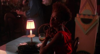 Movie still from “Mo' Better Blues” (1990), directed by Spike Lee – A woman sitting in front of a table with a lit lamp; Close Up shot, Over the shoulder angle