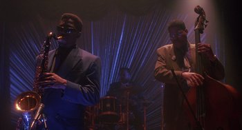 Movie still from “Mo' Better Blues” (1990), directed by Spike Lee – A couple of people that are standing up in a room; Medium shot, Low angle