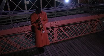 Movie still from “Mo' Better Blues” (1990), directed by Spike Lee – A man standing on a bridge holding a trumpet; Wide shot, High angle