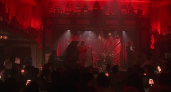 Movie still from “Mo' Better Blues” (1990), directed by Spike Lee – A group of people on a stage with a piano; Extreme Wide shot, High angle