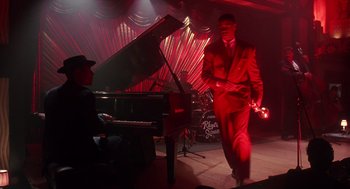 Movie still from “Mo' Better Blues” (1990), directed by Spike Lee – A man in a suit and hat walking in front of a piano; Wide shot, High angle