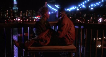 Movie still from “Mo' Better Blues” (1990), directed by Spike Lee – A man and a woman sitting on top of a wooden bench; Wide shot, Low angle