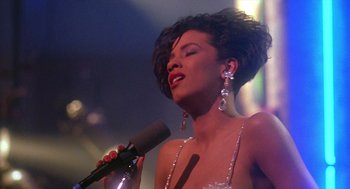 Movie still from “Mo' Better Blues” (1990), directed by Spike Lee – A woman holding a microphone in front of a microphone stand; Close Up shot, Low angle