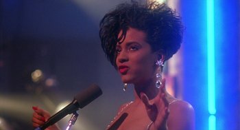 Movie still from “Mo' Better Blues” (1990), directed by Spike Lee – A woman is speaking into a microphone at a party; Close Up shot, Low angle