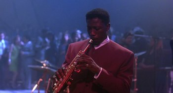 Movie still from “Mo' Better Blues” (1990), directed by Spike Lee – A man in a red jacket playing a red saxophone; Medium shot, Low angle
