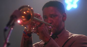 Movie still from “Mo' Better Blues” (1990), directed by Spike Lee – A man holding a trumpet while wearing a suit and tie; Close Up shot, Low angle