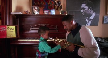 Movie still from “Mo' Better Blues” (1990), directed by Spike Lee – A man and a boy play with their musical instruments in front of a piano; Medium shot, Low angle