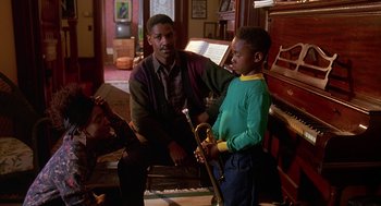 Movie still from “Mo' Better Blues” (1990), directed by Spike Lee – A man sitting next to a boy holding a trumpet; Medium shot, High angle