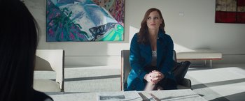 Movie still from “Molly's Game” (2017), directed by Aaron Sorkin – A woman sitting in front of a painting on a table; Medium shot, Over the shoulder angle