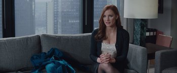 Movie still from “Molly's Game” (2017), directed by Aaron Sorkin – A woman sitting on top of a couch in a living room; Medium shot, Over the shoulder angle