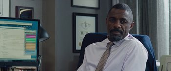 Movie still from “Molly's Game” (2017), directed by Aaron Sorkin – A man sitting in an office chair in front of a picture; Close Up shot, Over the shoulder angle