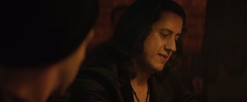 Movie still from “Molly's Game” (2017), directed by Aaron Sorkin – A man with long black hair sitting in a dark room; Close Up shot, Over the shoulder angle