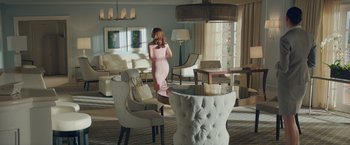 Movie still from “Molly's Game” (2017), directed by Aaron Sorkin – A woman in a pink dress in a living room with white furniture; Wide shot, High angle