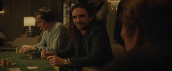 Movie still from “Molly's Game” (2017), directed by Aaron Sorkin – A man sitting at a table with a watch; Close Up shot, Over the shoulder angle