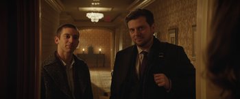 Movie still from “Molly's Game” (2017), directed by Aaron Sorkin – Two men in suits and ties standing in a hallway; Medium shot, Low angle