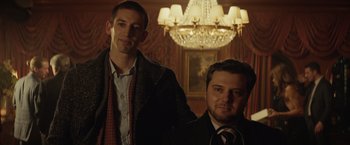 Movie still from “Molly's Game” (2017), directed by Aaron Sorkin – A couple of men standing next to each other in front of a chandelier; Medium shot, Low angle