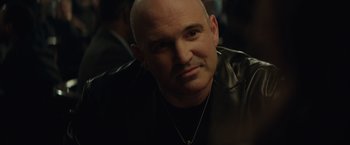 Movie still from “Molly's Game” (2017), directed by Aaron Sorkin – A man with a bald head wearing a leather jacket; Close Up shot, Over the shoulder angle