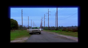 Movie still from “Monster” (2003), directed by Patty Jenkins – A car driving down a road next to power lines; Wide shot, Low angle