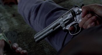 Movie still from “Monster” (2003), directed by Patty Jenkins – A gun that is laying on a persons arm; Extreme Close Up shot, Overhead angle