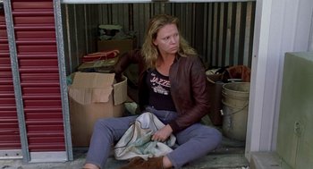 Movie still from “Monster” (2003), directed by Patty Jenkins – A woman sitting on the ground in front of a pile of boxes; Medium shot, Low angle