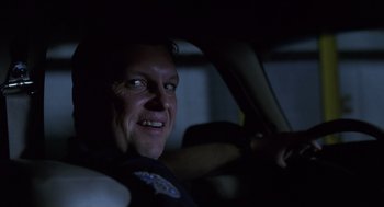 Movie still from “Monster” (2003), directed by Patty Jenkins – A man in a police uniform sitting in the driver's seat of a car at night; Close Up shot, Low angle