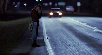 Movie still from “Monster” (2003), directed by Patty Jenkins – A woman standing on the side of a road while talking on a cell phone; Wide shot, Over the shoulder angle