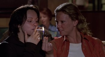 Movie still from “Monster” (2003), directed by Patty Jenkins – A woman lighting a cigarette with another woman looking on; Close Up shot, High angle
