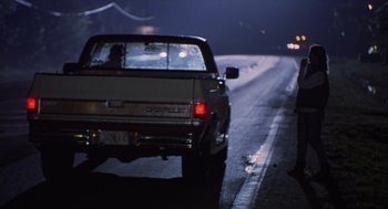 Movie still from “Monster” (2003), directed by Patty Jenkins – A truck driving down a street at night with lights on; Wide shot, Over the shoulder angle