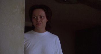 Movie still from “Monster” (2003), directed by Patty Jenkins – A woman in a white t - shirt is standing in a room; Close Up shot, Over the shoulder angle