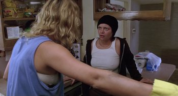Movie still from “Monster” (2003), directed by Patty Jenkins – Two women in a kitchen , one of whom is wearing a black hat; Medium shot, Over the shoulder angle