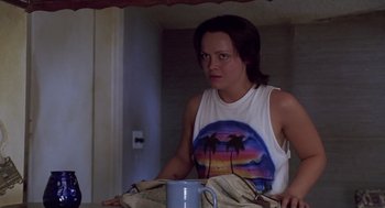 Movie still from “Monster” (2003), directed by Patty Jenkins – A woman standing in front of a mirror holding a coffee mug; Medium shot, Low angle