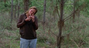 Movie still from “Monster” (2003), directed by Patty Jenkins – A woman standing in the middle of a forest smoking a cigarette; Medium shot, High angle
